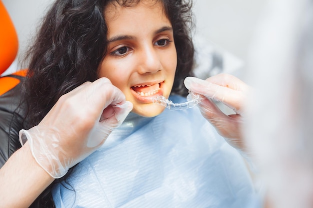 Chica adolescente con frenos dentista pone frenos en el cuidado dental de la niña y el concepto de ortodoncia