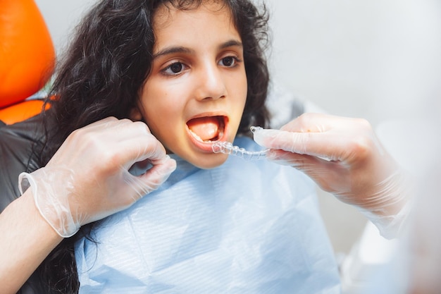 Chica adolescente con frenos dentista pone frenos en el cuidado dental de la niña y el concepto de ortodoncia