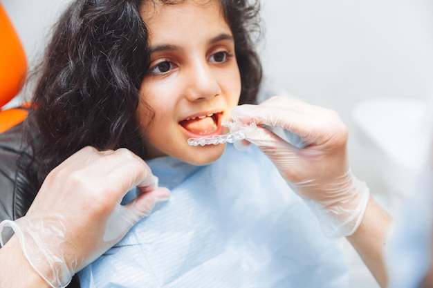 Chica adolescente con frenos dentista pone frenos en el cuidado dental de la niña y el concepto de ortodoncia