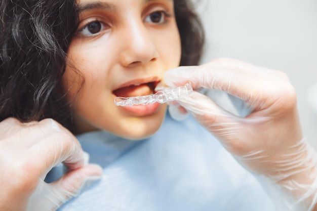 Chica adolescente con frenos dentista pone frenos en el cuidado dental de la niña y el concepto de ortodoncia