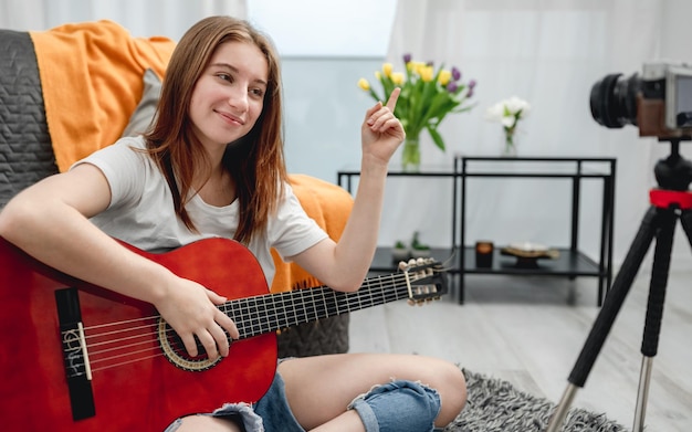 Chica adolescente con guitarra grabando streaning con cámara