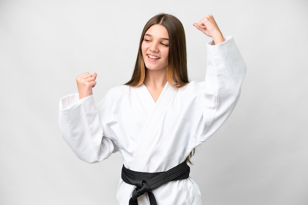 Chica adolescente haciendo karate sobre fondo blanco aislado celebrando una victoria