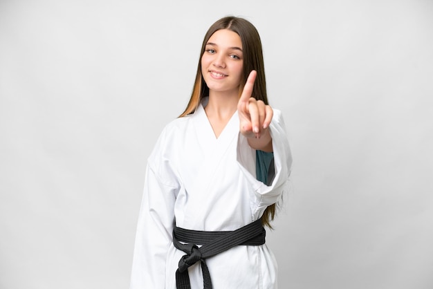 Chica adolescente haciendo karate sobre fondo blanco aislado mostrando y levantando un dedo