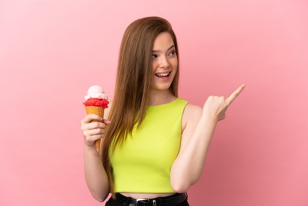 Foto chica adolescente con un helado de cucurucho sobre fondo rosa aislado con la intención de darse cuenta de la solución mientras levanta un dedo hacia arriba