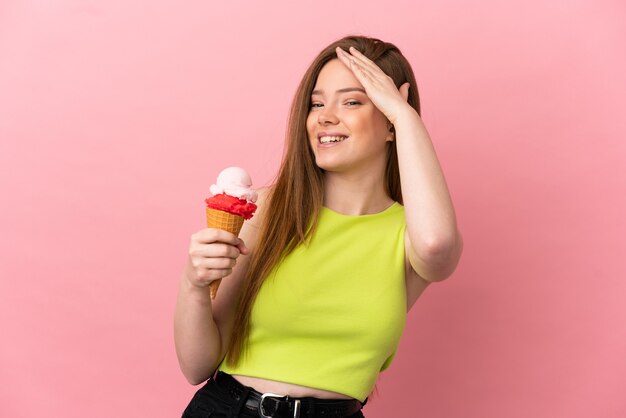 Chica adolescente con un helado de cucurucho sobre fondo rosa aislado sonriendo mucho