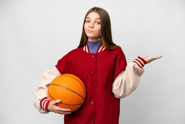 Chica adolescente jugando baloncesto sobre fondo blanco aislado que tiene dudas mientras levanta las manos