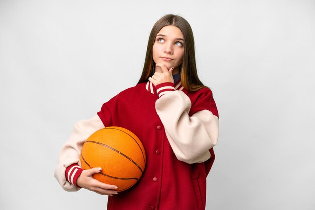 Chica adolescente jugando baloncesto sobre fondo blanco aislado que tiene dudas