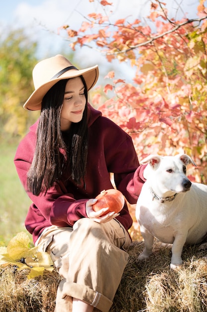 Chica adolescente jugando con perro en el jardín de otoño