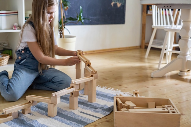 Chica adolescente jugando pista constructor block tower con bola metálica materiales maria montessori