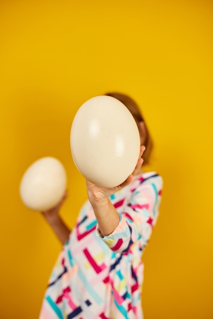 Chica adolescente juguetona feliz sosteniendo huevos de avestruz