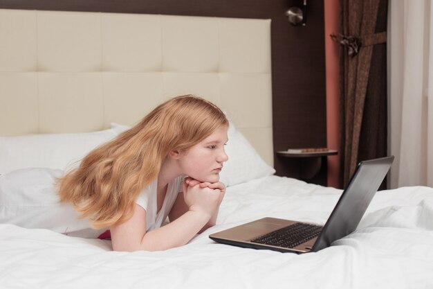 Chica adolescente con laptop en la cama