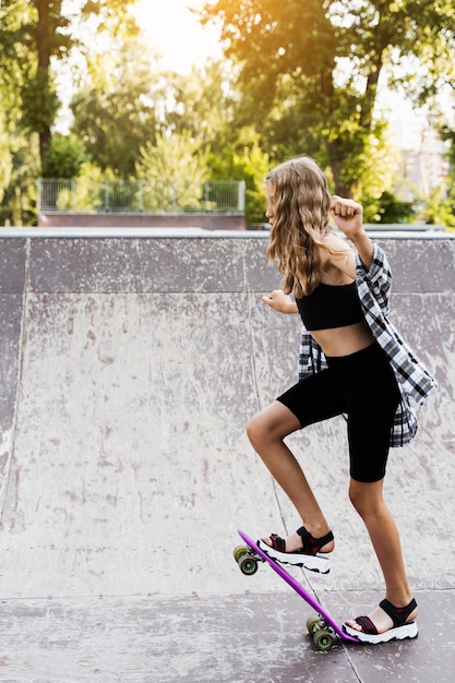 Chica adolescente lista para montar en penny board en el parque de patinetas Equipo deportivo para niños Estilo de vida extremo