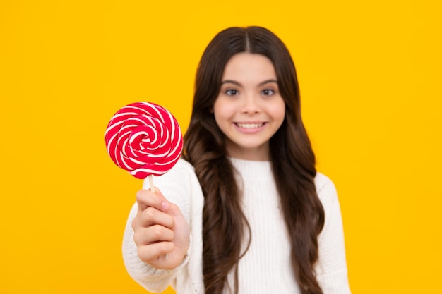 Chica adolescente mantenga caramelo de piruleta sobre fondo amarillo tienda de dulces Adolescente con chupones de dulces Cara feliz emociones positivas y sonrientes de chica adolescente