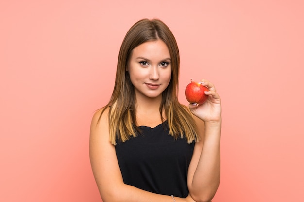 Chica adolescente con una manzana sobre pared aislada