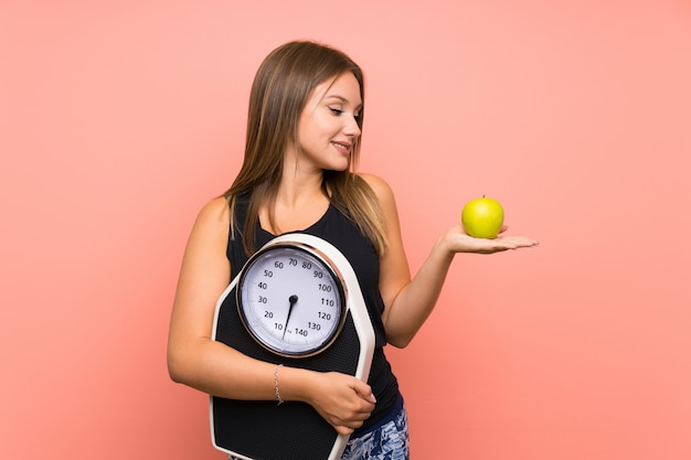 Chica adolescente con máquina de pesaje sobre fondo aislado