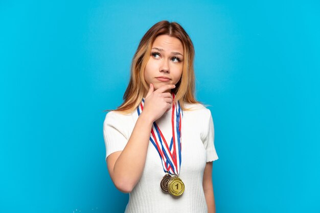 Chica adolescente con medallas aisladas teniendo dudas