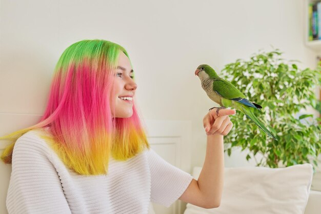 Chica adolescente de moda con loro verde en su mano