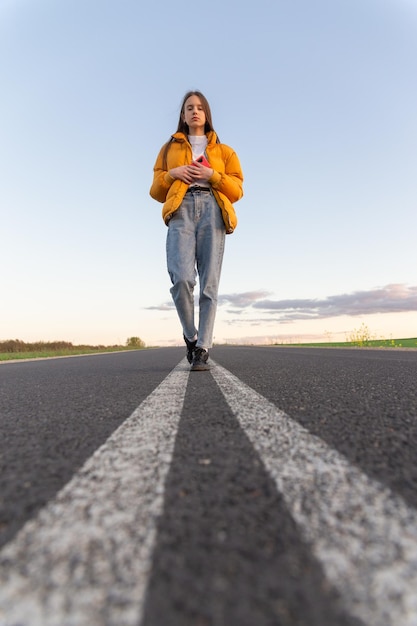 Una chica adolescente moderna y genial posa en un camino solitario