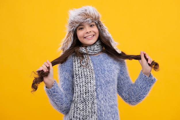 Chica adolescente moderna con suéter y gorro de punto sobre fondo amarillo aislado Cara feliz emociones positivas y sonrientes de chica adolescente