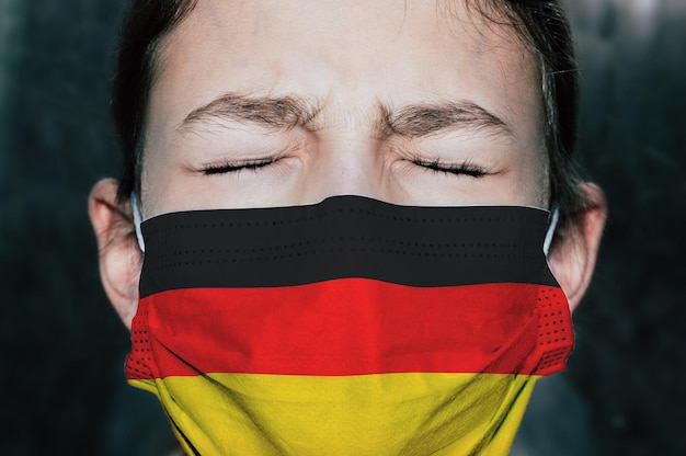 Chica adolescente molesta con máscara médica con la bandera de Alemania