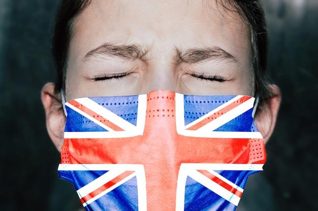 Chica adolescente molesta con máscara médica con bandera del Reino Unido