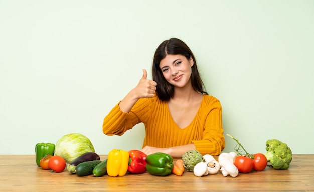 Chica adolescente con muchas verduras con los pulgares arriba porque algo bueno ha sucedido.