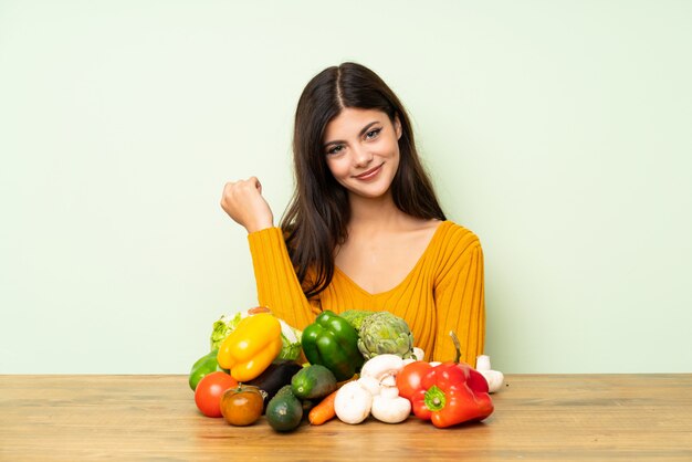 Chica adolescente con muchas verduras sobre pared verde