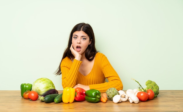 Chica adolescente con muchas verduras sorprendida y conmocionada mientras mira a la derecha