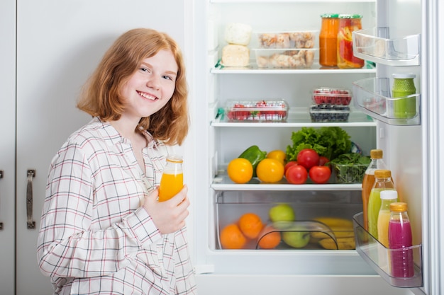 Chica adolescente en la nevera con comida