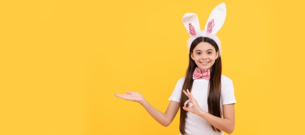 Chica adolescente en orejas de conejo presentando productos o ventas de compras Cartel horizontal de niño de Pascua Encabezado de banner web de espacio de copia de niño de conejito