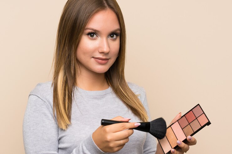 Foto chica adolescente con paleta de maquillaje sobre pared aislada