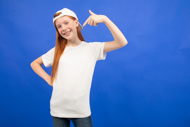 chica adolescente pelirroja en una camiseta blanca con un diseño muestra la clase azul