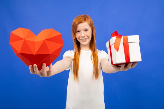 Chica adolescente pelirroja sostiene una caja de regalo azul