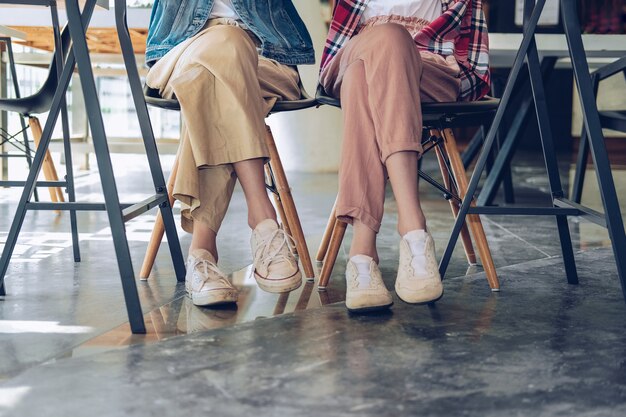 Chica adolescente piernas usando zapatillas sentado hablando juntos