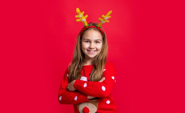 Chica adolescente positiva usar suéter y astas de ciervo en vacaciones de navidad feliz navidad