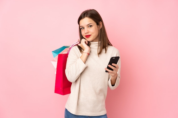 Chica adolescente en rosa con bolsas de compras y un teléfono móvil