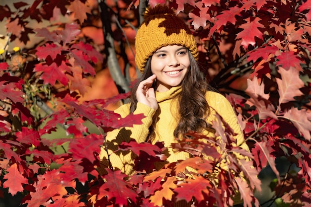 Chica adolescente sobre fondo de otoño otoño cara de niño feliz con sombrero en hojas de otoño sobre fondo natural