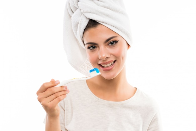 Chica adolescente sobre pared blanca aislada cepillando sus dientes