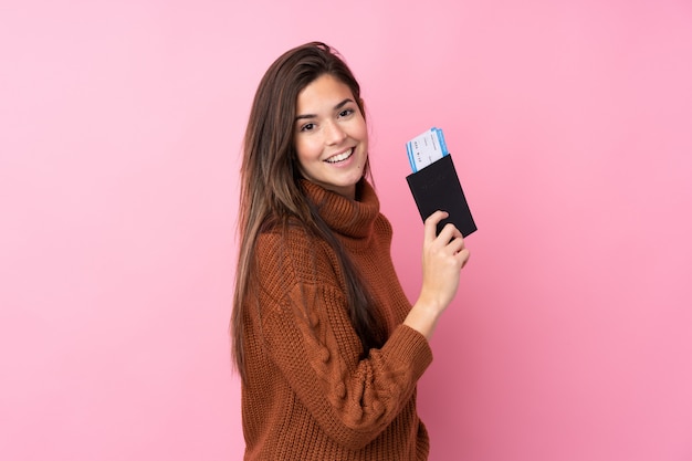 Chica adolescente sobre pared rosa aislado feliz en vacaciones con pasaporte y boletos de avión