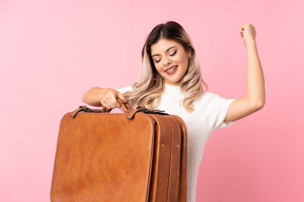 Foto chica adolescente sobre rosa aislado sosteniendo un maletín vintage