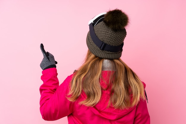 Chica adolescente con sombrero de invierno sobre pared rosa aislado
