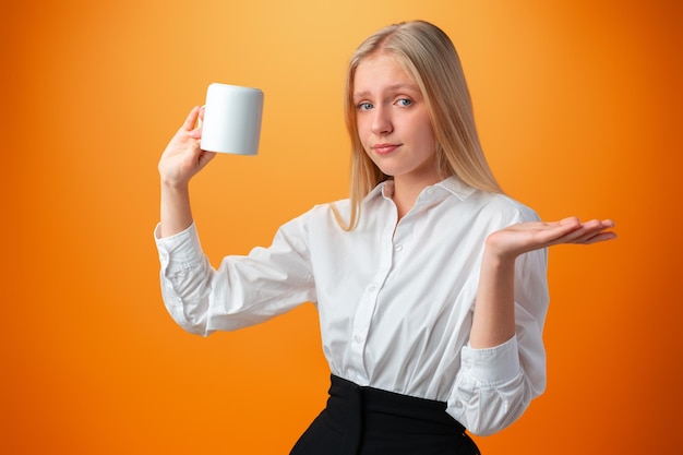 Chica adolescente soñolienta sosteniendo una taza de café caliente sobre fondo naranja