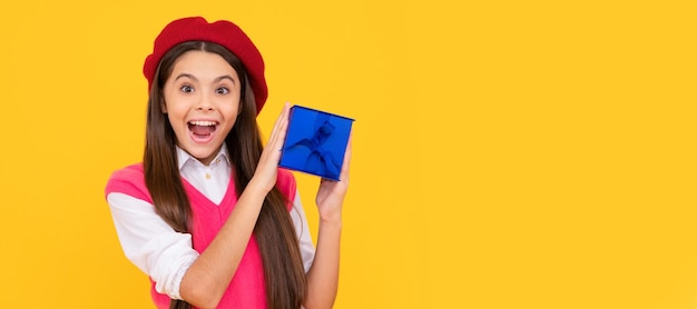 Chica adolescente sorprendida en boina francesa sostener presente o caja de regalo sobre fondo amarillo sorpresa de cumpleaños Niña con cartel horizontal de regalo Encabezado de banner con espacio de copia