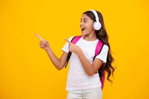 Chica adolescente sorprendida Colegiala en auriculares sobre fondo de estudio aislado Concepto de escuela y música