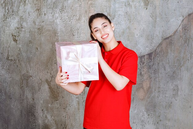 Chica adolescente sosteniendo una caja de regalo rosa envuelta con cinta blanca