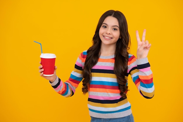 Chica adolescente sosteniendo una taza caliente de café o té Niño con taza para llevar sobre fondo amarillo bebida energética matutina bebida Adolescente feliz emociones positivas y sonrientes de chica adolescente