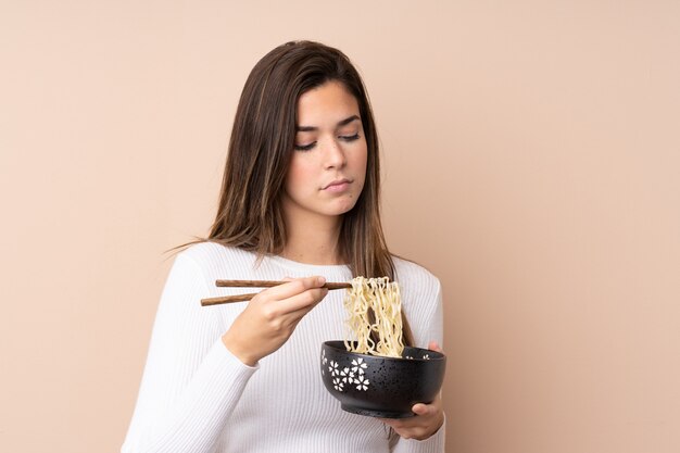 Chica adolescente sosteniendo un tazón de fideos con palillos