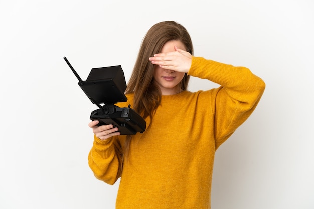 Chica adolescente sosteniendo un teledirigido drone sobre fondo blanco aislado cubriendo los ojos con las manos. No quiero ver algo