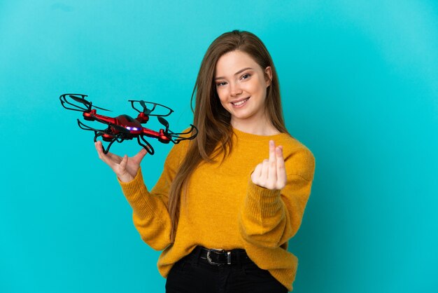 Chica adolescente sosteniendo un zumbido sobre fondo azul aislado haciendo gesto de dinero