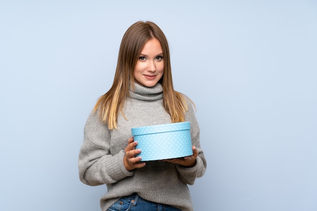 Chica adolescente con suéter sobre caja de regalo sosteniendo aislado